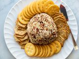 The best cheese ball is in the center of a platter and surrounded by crackers.