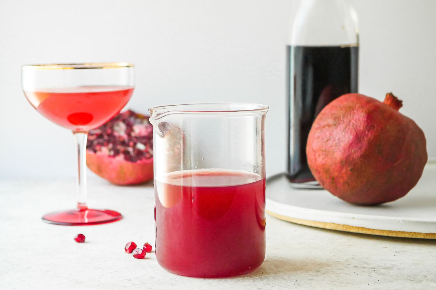 Sirop de grenadine dans un verre à cocktail avec une grenadine et des grenades en arrière-plan.