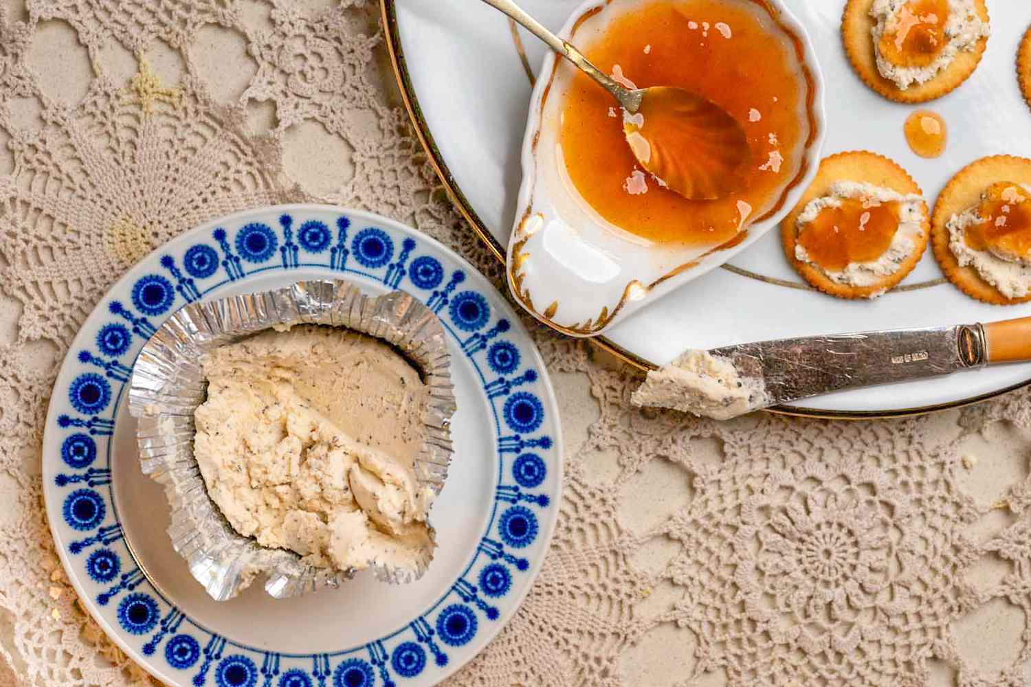 Vue aérienne d'une petite assiette de fromage Boursin à côté d'une grande assiette avec un couteau à fromage, un bol de chutney de mangue et des crackers Ritz garnis de fromage Boursin et de chutney de mangue, le tout sur une surface tissée élaborée (Apéritif 3 Ingrédients de l'Ami)