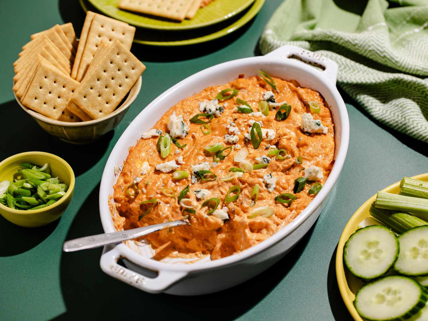 Un plat rempli de chicken dip à côté d'un bol rempli de crackers.