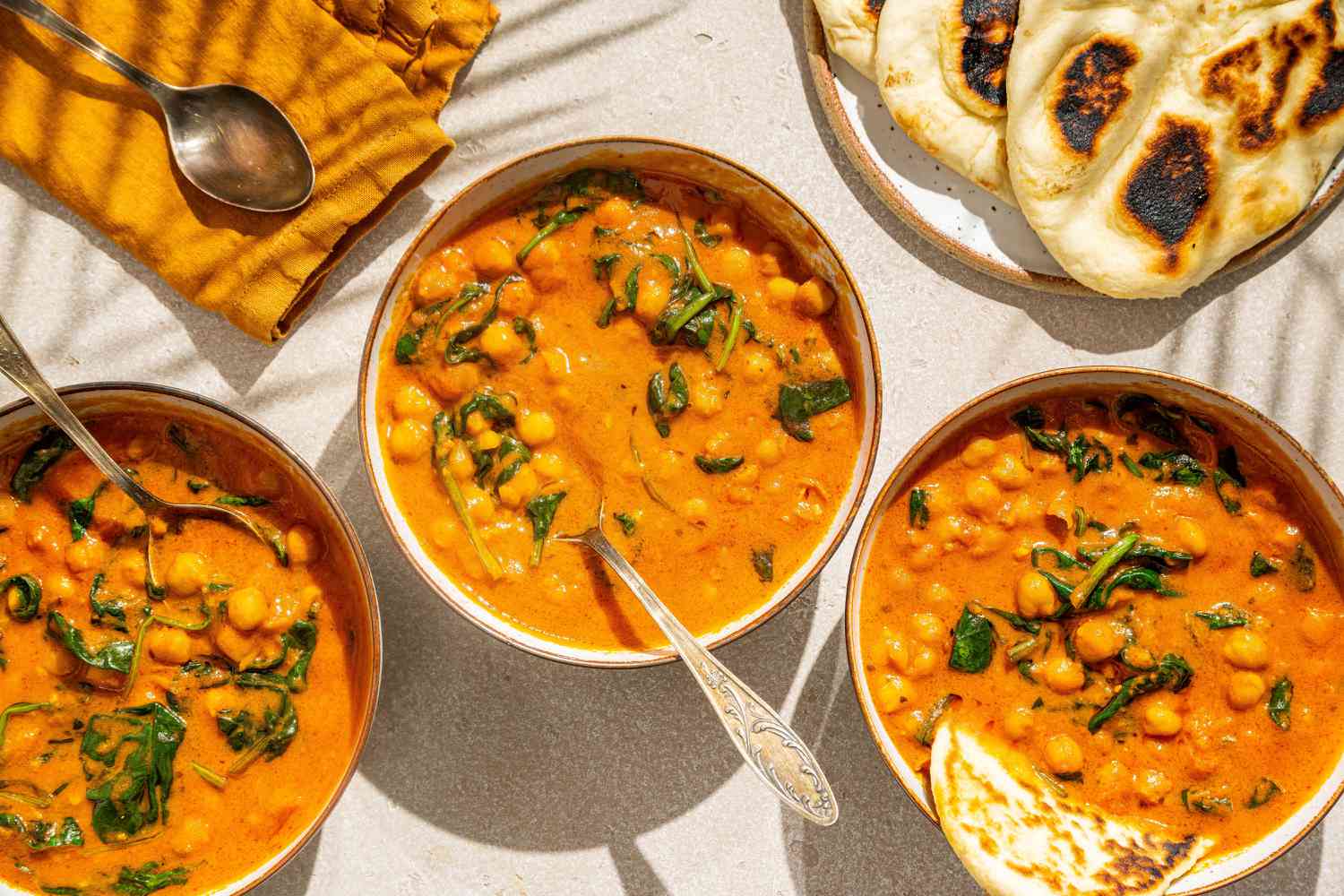 3 bols de curry de pois chiches faciles avec des cuillères, naan à côté