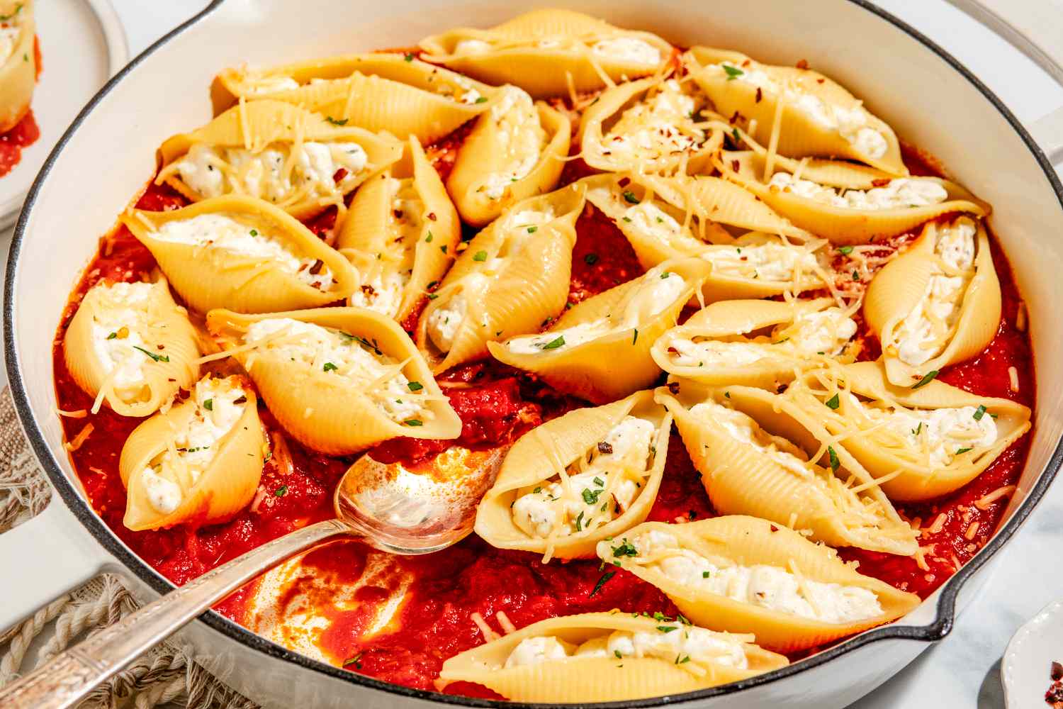 Coquilles farcies à la cuisinière dans une grande poêle avec une grande cuillère de service