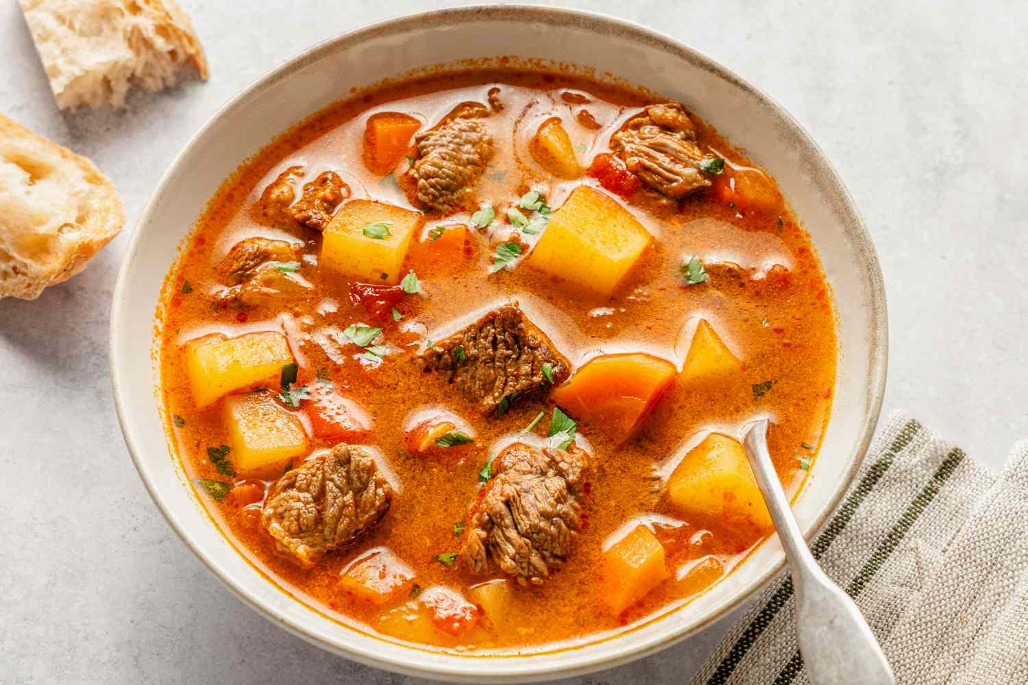 Vue aérienne d'un bol de goulash hongrois avec une cuillère et à côté de quelques morceaux de pain