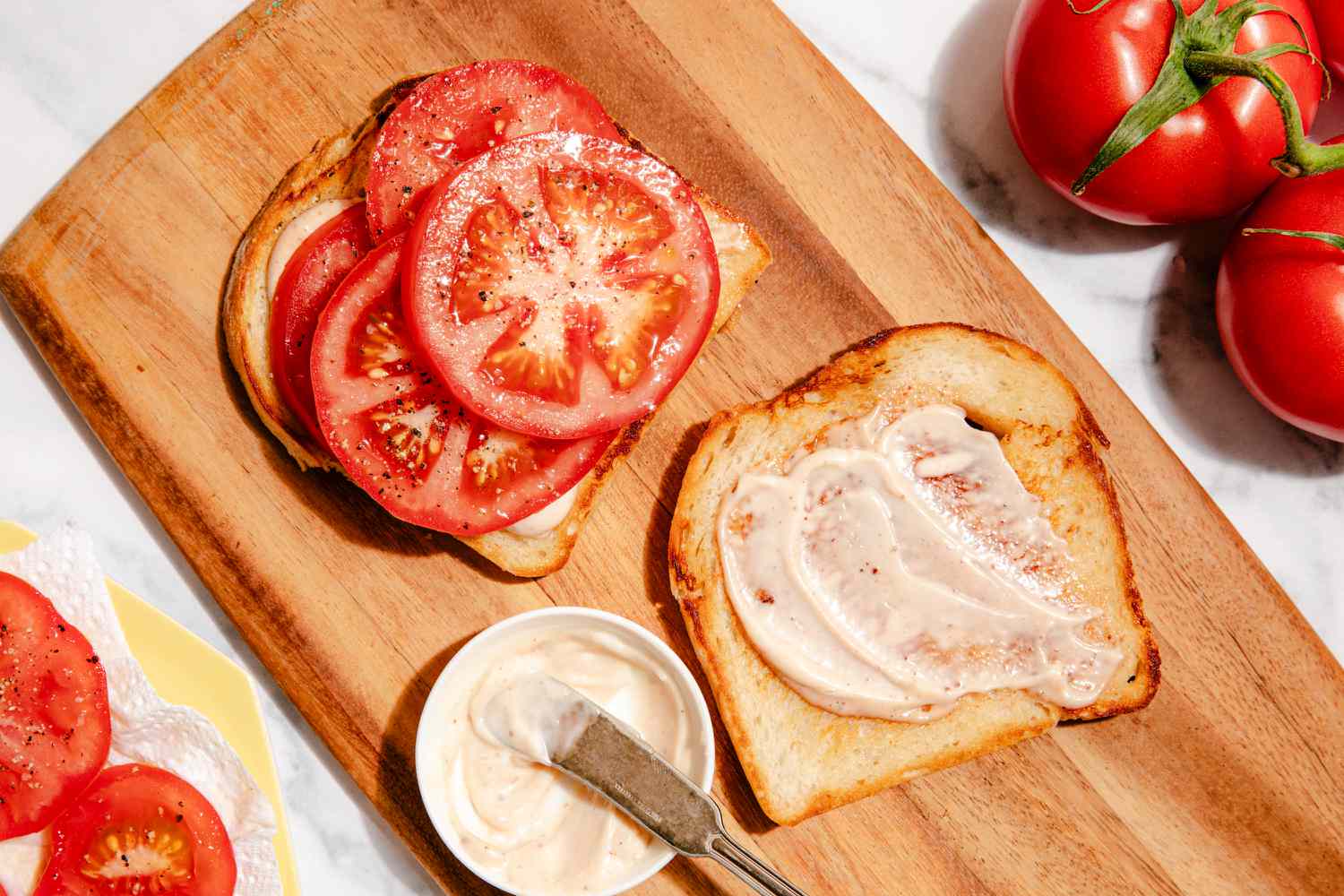 sandwich à la tomate en cours d'assemblage sur une planche à découper