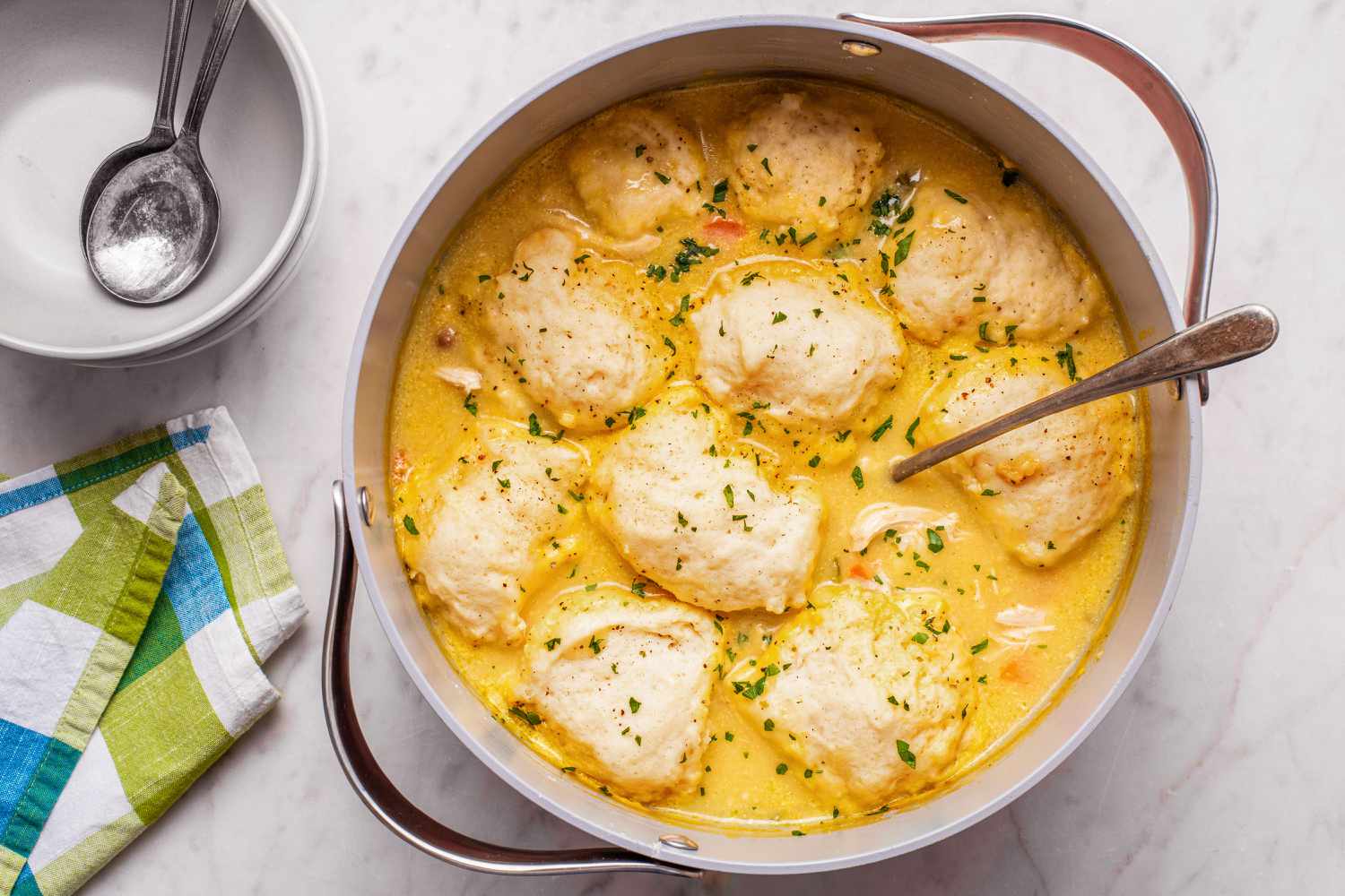 Dumplings de poulet faciles dans une casserole, bols, cuillères et serviettes sur le côté