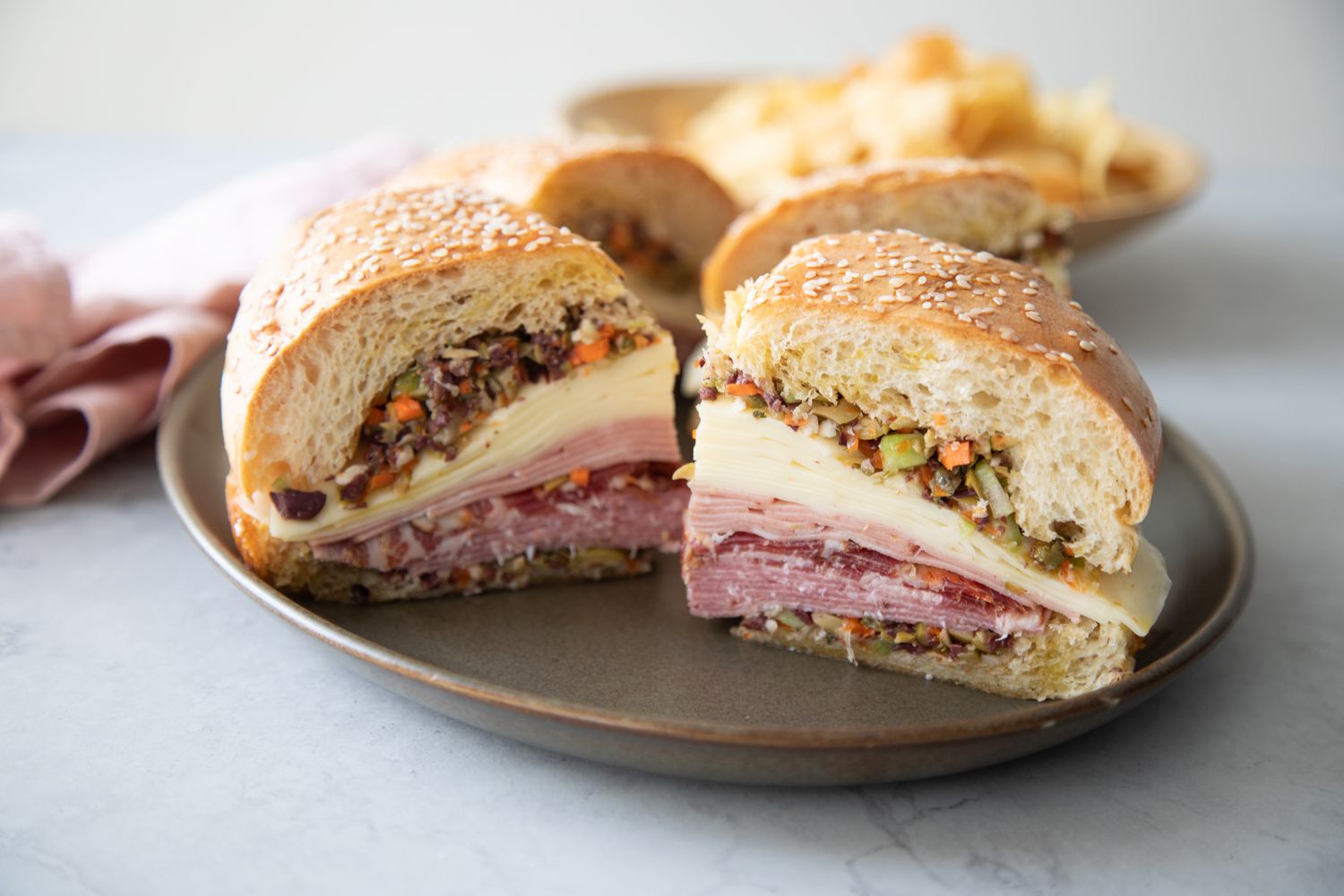 A Plate with Quarters of a Classic Muffuletta Sandwich Made with Cold Cuts, Cheese, and Olives