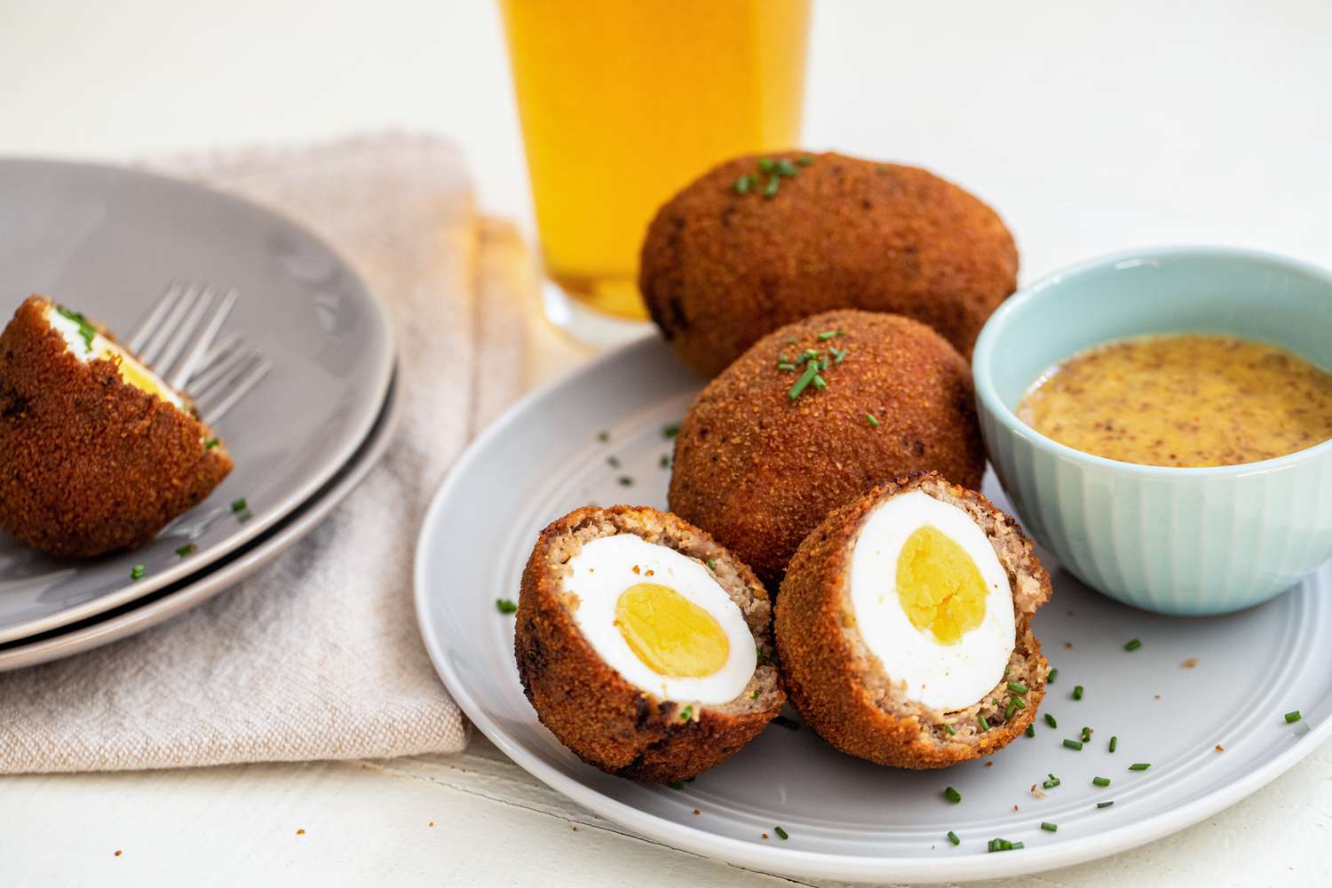 Scotch eggs coupés en deux sur une assiette avec une sauce miel-moutarde.