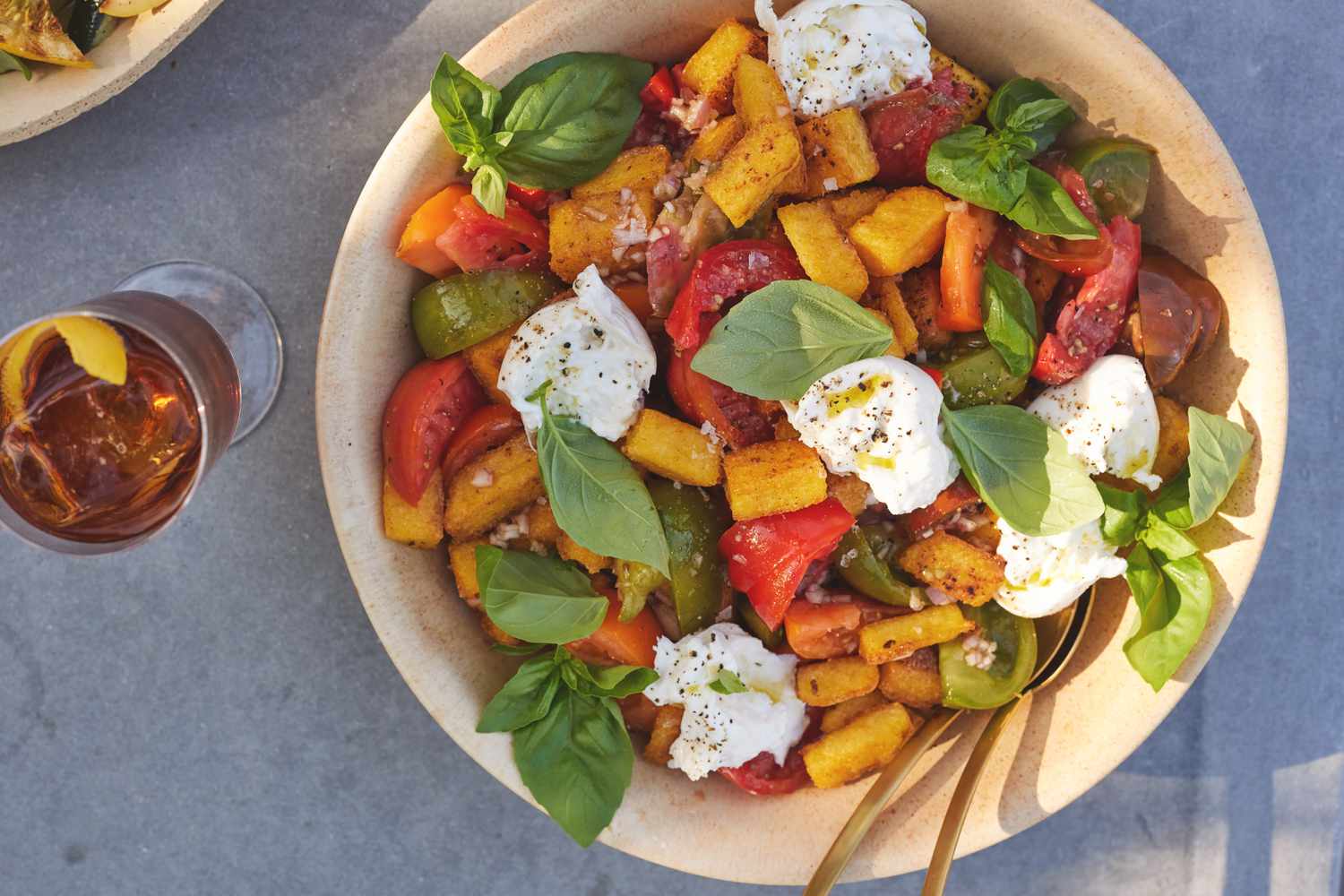 Bol de Panzanella de Polenta Frite avec Tomate, Basilic et Burrata avec une Boisson sur une Table