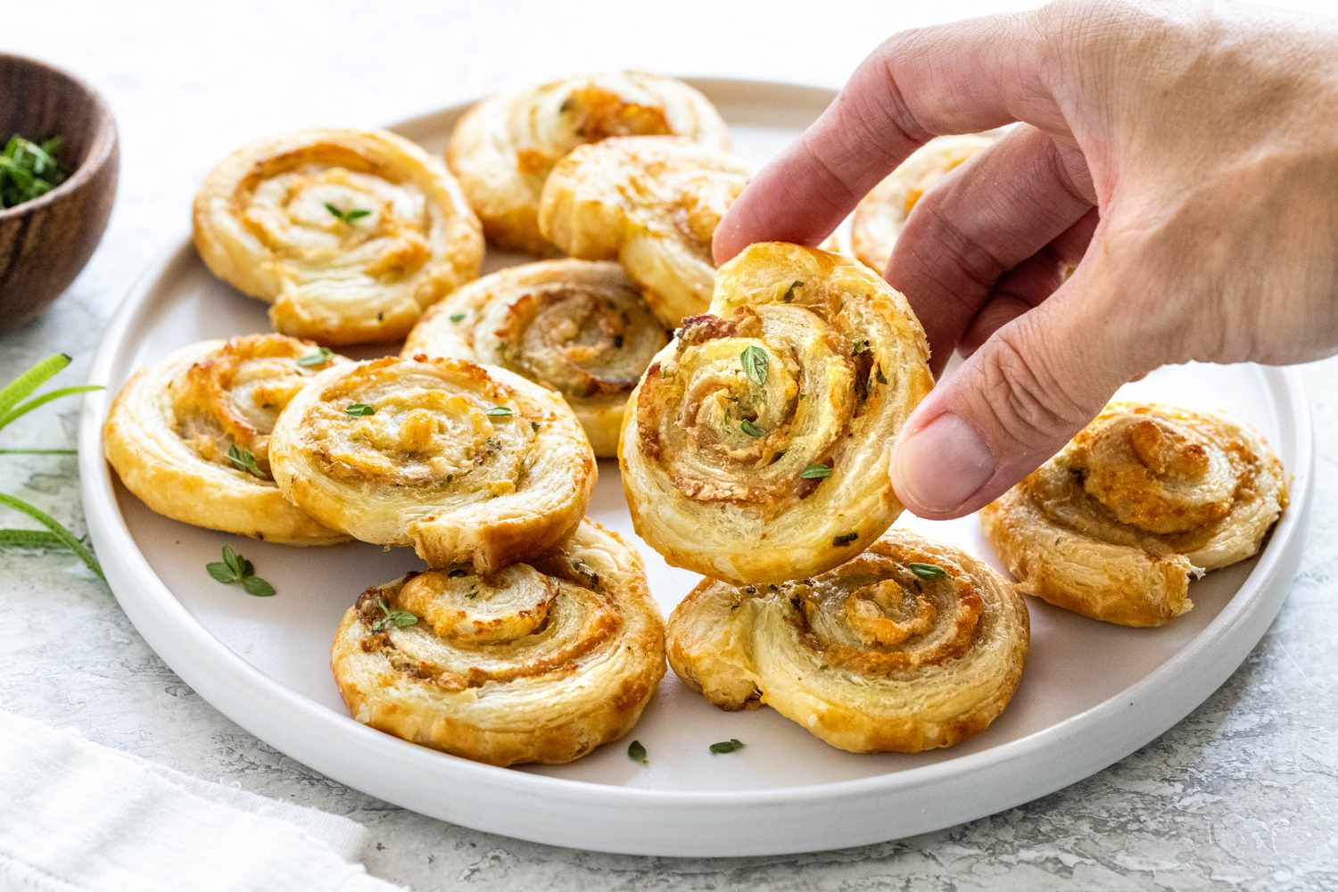 A person picking up a crispy prosciutto and parmesan pinwheels