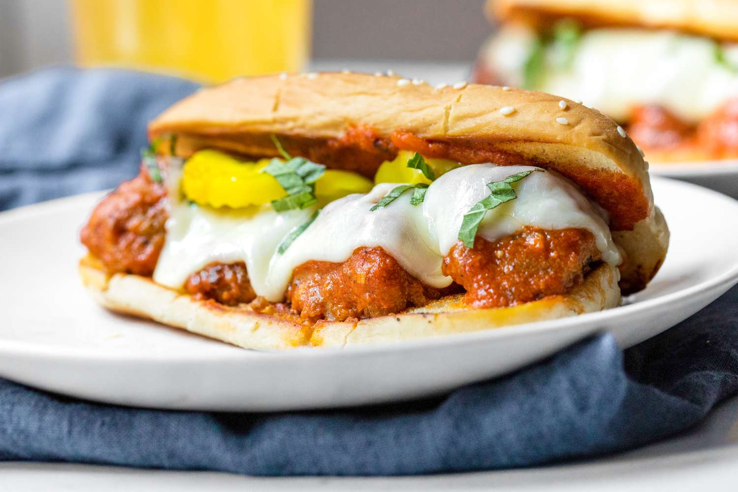 Une assiette de sandwich aux boulettes de viande surmontée de poivrons banane et de basilic.