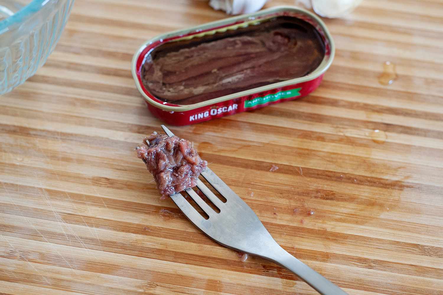 Anchois sur une fourchette à côté de la boîte.